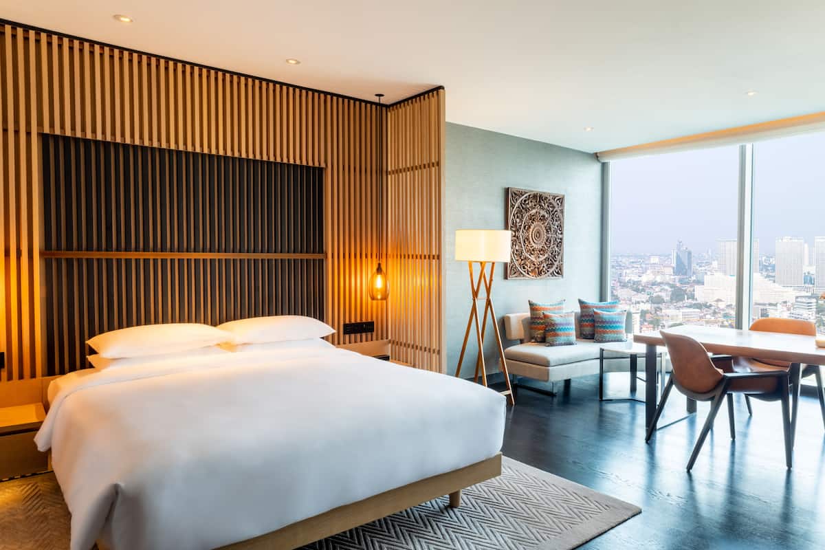 Una habitación de hotel moderna con una cama grande, un escritorio y vistas a la ciudad.