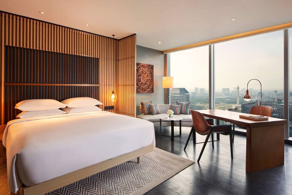 Una habitación de hotel moderna con una cama grande, un escritorio y vistas a la ciudad.