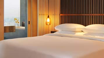 Un dormitorio moderno con una cama grande, cabecera de madera y vista a la ciudad a través de un ventanal.