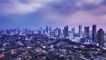 Un paisaje urbano al atardecer con edificios altos y una zona residencial densamente poblada.