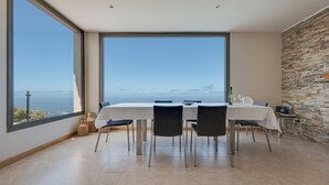 A dining area with a large table, chairs, and a view of the sea. - Holiday Home ‘Casa Santa Úrsula’ with Sea View, Pool, Wi-Fi & Garden (Santa ursula)