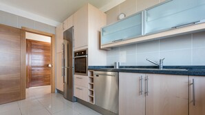 A modern kitchen with stainless steel appliances, wooden cabinets, and a tiled backsplash. - Holiday Home ‘Casa Santa Úrsula’ with Sea View, Pool, Wi-Fi & Garden (Santa ursula)