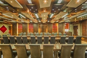 Une salle de conférence dotée de plusieurs tables et chaises, de lambris en bois aux murs et d’un éclairage encastré.