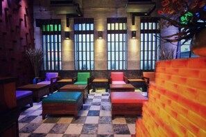 A checkered floor with multiple seating areas, including sofas and chairs, arranged in a semi-circular layout. - Pak Ping Ing Tang Boutique Hotel (Nonthaburi)