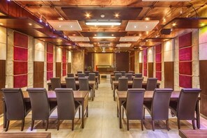 A conference room with multiple tables and chairs, a wooden ceiling, and a central stage area.