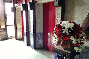 A hallway with a red door, a flower arrangement on a table, and patterned walls. - Pak Ping Ing Tang Boutique Hotel (Nonthaburi)