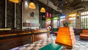 A restaurant interior with a checkered floor, wooden benches, and a brick pillar. - Pak Ping Ing Tang Boutique Hotel (Nonthaburi)