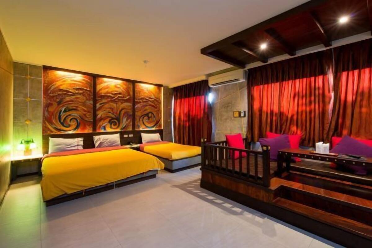 Een hotelkamer met twee bedden, een bank, een trap en een groot abstract schilderij aan de muur.