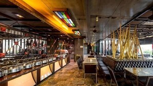 A restaurant interior with a stone floor, metal counters, and a seating area with tables and benches. - Pak Ping Ing Tang Boutique Hotel (Nonthaburi)