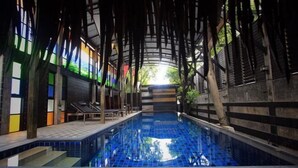 An indoor swimming pool with a blue tiled floor, surrounded by wooden beams and a glass ceiling. - Pak Ping Ing Tang Boutique Hotel (Nonthaburi)