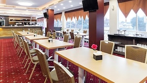 A restaurant with multiple tables and chairs, a counter area, and large windows.