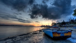 A beach with boats and a sunset.