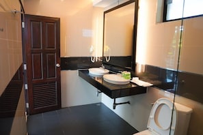 A bathroom with a wooden door, two sinks, a mirror, and a toilet. - Silver Sand Samed Hotel & Resort (Rayong)