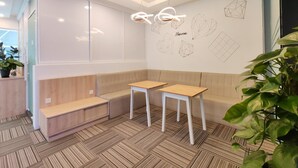 A modern interior with a wooden bench, two tables, and geometric wall art. - Orange Business Hotel Petaling Jaya (Petaling Jaya)