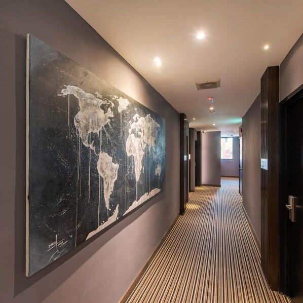A hallway with a large abstract world map mural, a patterned carpet, and a door with a number sign. - Orange Business Hotel Petaling Jaya (Petaling Jaya)