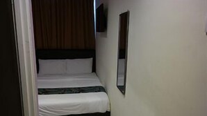 A narrow room with a bed, a wall-mounted TV, and a door. - Clover Hotel Port Dickson (Port Dickson)