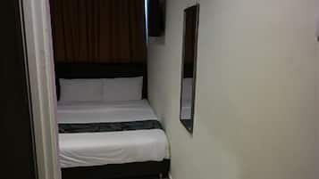A narrow room with a bed, a wall-mounted TV, and a door.
