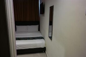 A narrow room with a bed, a wall-mounted TV, and a door. - Clover Hotel Port Dickson (Port Dickson)