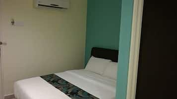 A single bed with a white mattress and a floral-patterned bedspread, a black headboard, and a teal accent wall.
