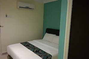 Un lit simple avec un matelas blanc et une couvre-lit à motifs floraux, une tête de lit noire et un mur d’accent de couleur turquoise.
