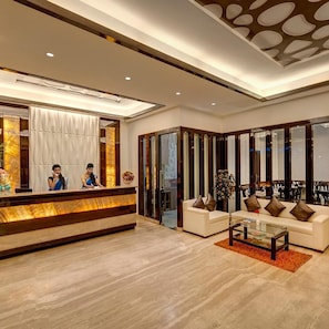 A hotel lobby with a reception desk, seating area, and a view of the interior.