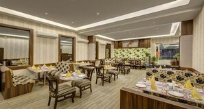 A restaurant with multiple dining tables and chairs, air conditioning units, and a patterned wall.