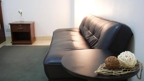 A dark brown leather sofa with a curved armrest and a small round table with two balls of yarn.