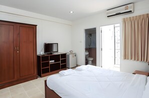 A bedroom with a bed, wardrobe, television, and a bathroom visible through an open door. - Baan Boonanan (Thanyaburi)