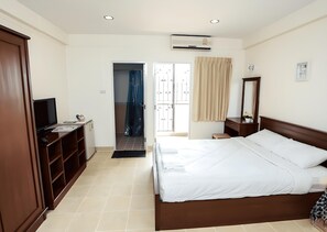 A hotel room with a bed, wardrobe, desk, and a bathroom with a shower. - Baan Boonanan (Thanyaburi)