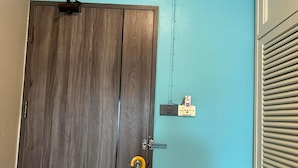 A wooden door with a yellow do not disturb sign, a light switch, and a power outlet on a teal wall. - Bbhouse Pattaya (Pattaya)