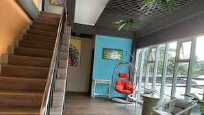 A staircase leading to a room with a hanging chair, a table, and a view through large windows. - Bbhouse Pattaya (Pattaya)