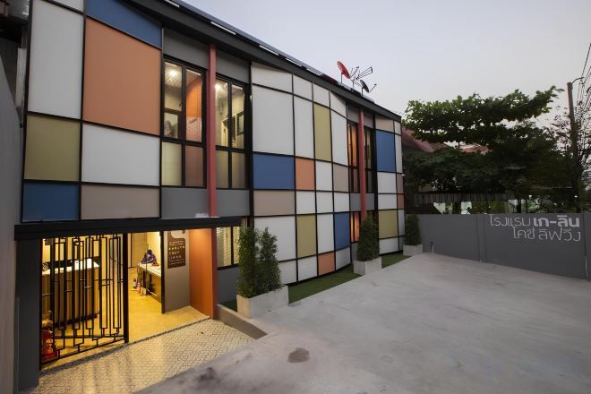 A modern building with a flat facade, large windows, and a visible entrance with a metal gate.