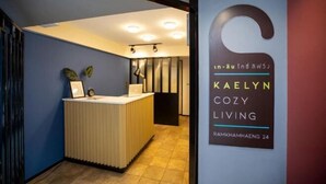 A reception area with a modern design, including a reception desk and a wall-mounted sign for Kaelyn Cozy Living. - Kaelyn Cozy Living (Bangkok)