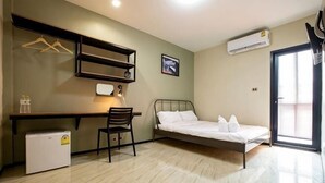 A compact room with a bed, desk, chair, and a small refrigerator. - Kaelyn Cozy Living (Bangkok)