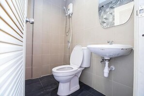 A bathroom with a toilet, sink, shower, and tiled walls. - Kaelyn Cozy Living (Bangkok)