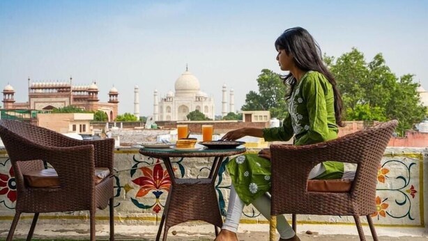 Una persona asseguda a una taula amb vista al Taj Mahal.