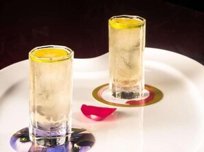 Two glasses of a clear beverage with a slice of lemon, placed on a white tray with a gold rim.