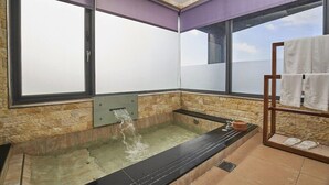 Ein Wellnessraum mit einer großen Badewanne, einem Fenster und einem Handtuchhalter.