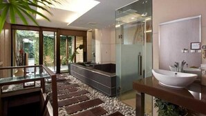 Ein modernes Badezimmer mit Duschkabine aus Glas, einer großen Badewanne und einem Holzwaschtisch mit weißem Waschbecken.