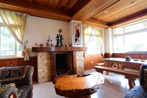 Une pièce chaleureuse avec une cheminée en pierre, un plafond en bois et une table à manger.