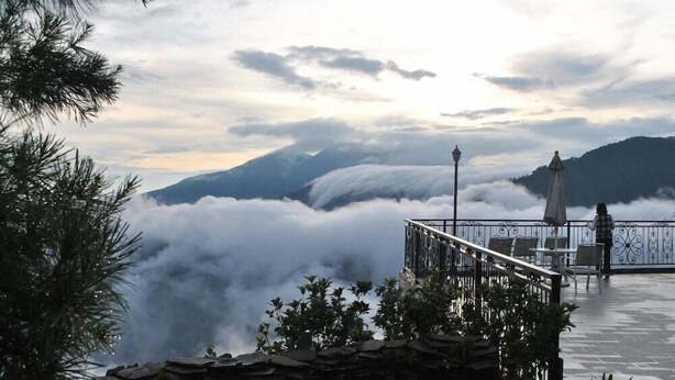 A terrace with a stone wall, a railing, and a view of clouds over mountains. - Star Villa (Nantou)