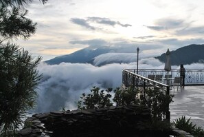 A terrace with a stone wall, a railing, and a view of clouds over mountains. - Star Villa (Nantou)
