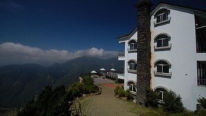 A multi-story building with a stone chimney, surrounded by lush greenery and a mountainous backdrop. - Star Villa (Nantou)