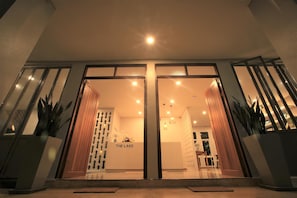 Entrada de hotel con diseño moderno, que presenta una puerta de vidrio y un letrero que dice 'THE LAKE'.