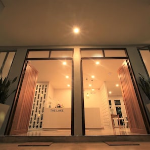 Entrada d'hotel de disseny modern, amb façana de vidre i detalls de fusta.