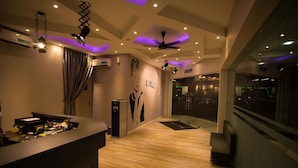 A modern hotel lobby with a reception desk, ceiling fans, and a large window overlooking the street. - Hollywood Hotel (Ipoh)