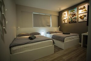A bedroom with two beds, a window, and wall art. - Hollywood Hotel (Ipoh)