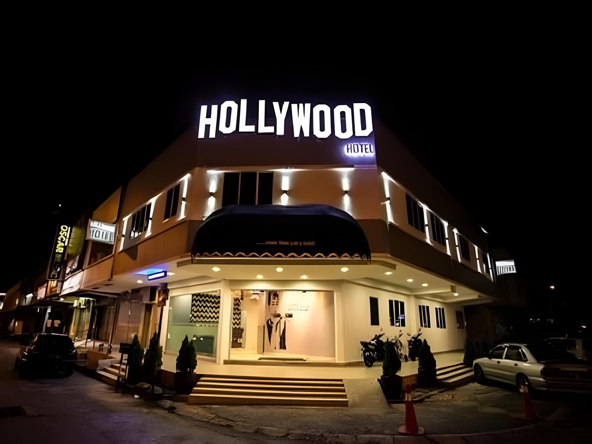 A hotel with a prominent 'HOLLYWOOD HOTEL' sign, a two-story structure, and a visible entrance with steps leading up to it.