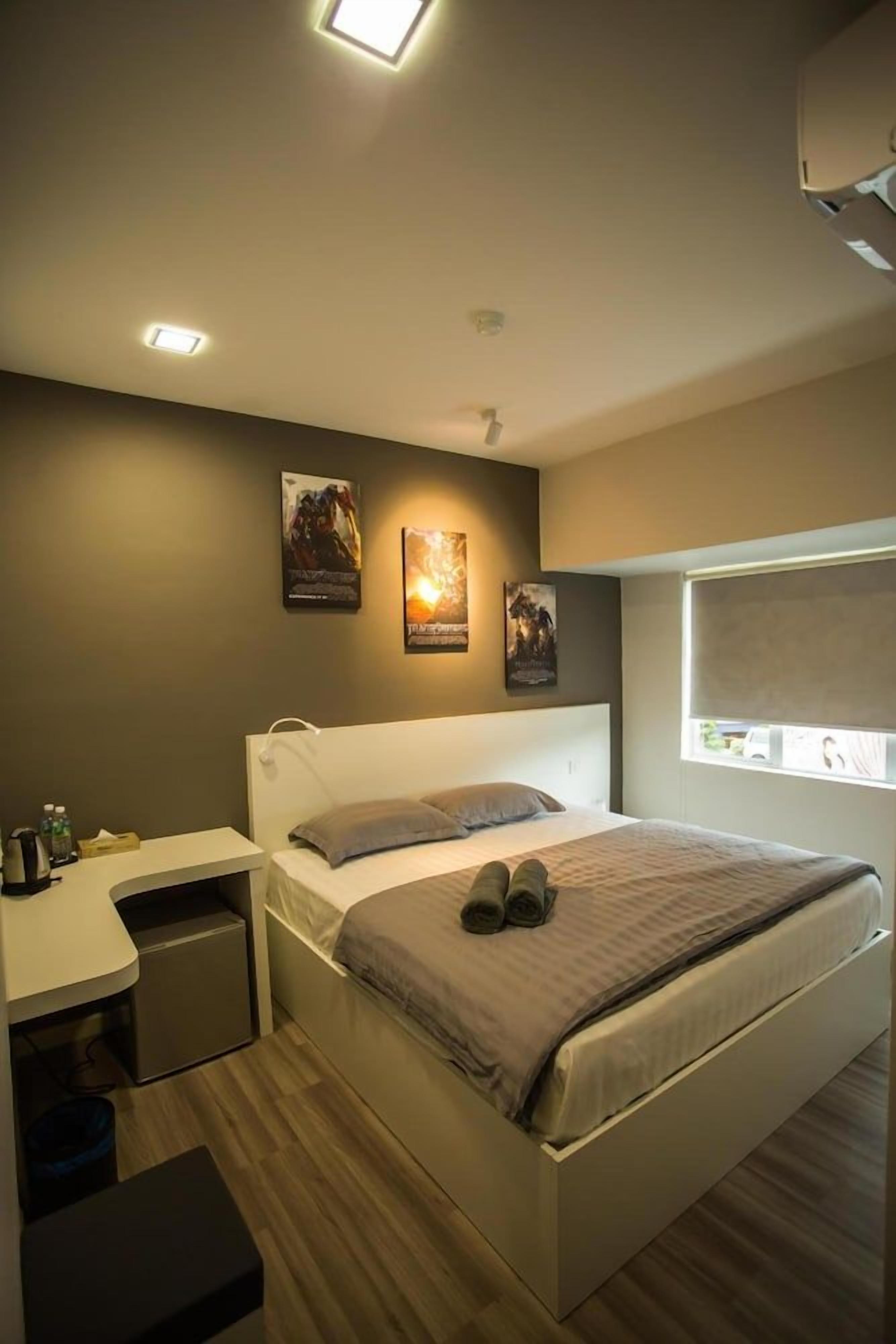 A modern bedroom with a bed, bedside table, and a window.