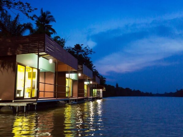 A waterfront property with a series of connected buildings, a dock, and a reflection on the water.